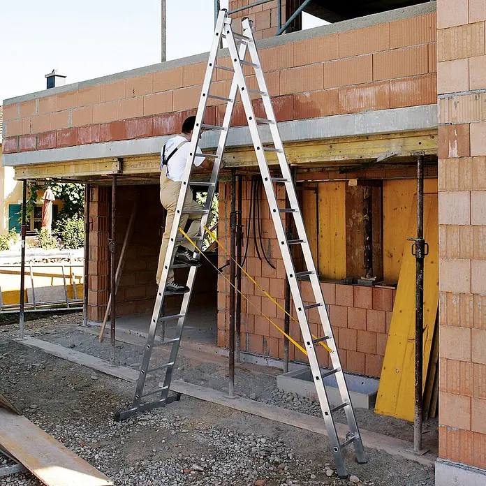 Zarges Mehrzweckleiter Kombileiter Combimaster Plus X 2x12 Sprossen - Anzahl Tritte: 12 Stk., Arbeitshöhe: 6.800 m, Aluminium - Aluminium-Klappleiter in A-Form auf Baustelle, ein Arbeiter steigt hinauf.