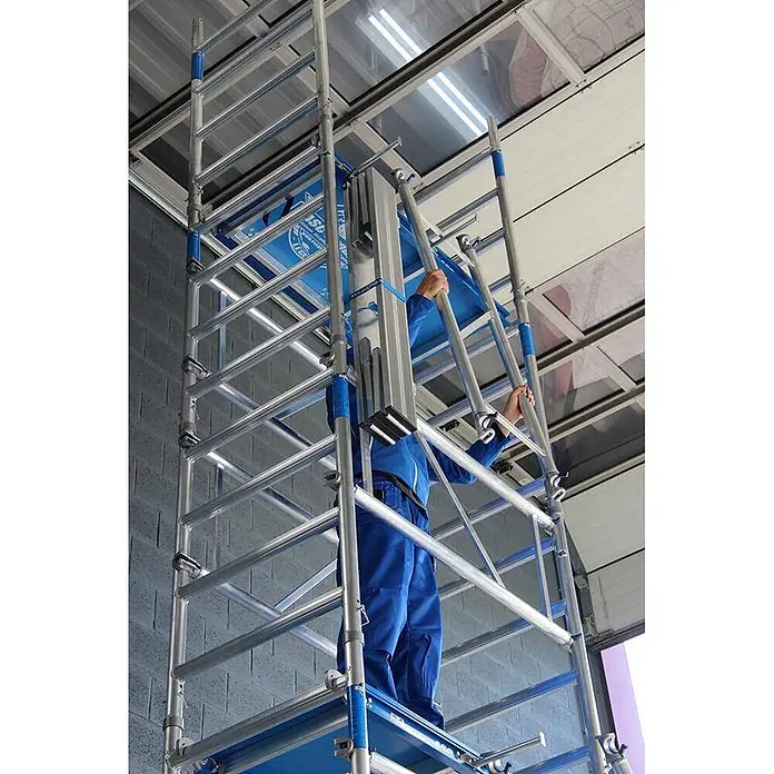 ASC Rollgerüst Rollgerüst XS-Tower (DIN EN 1004:2004) - Arbeitshöhe: 6.200 m - Person in Blau montiert ein modulares Gerüst aus silbernem und blauem Aluminium.