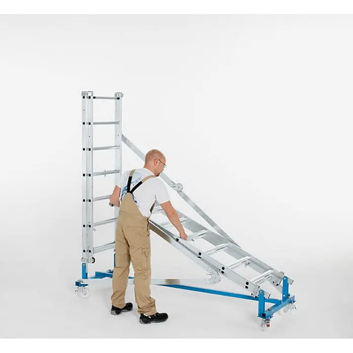 Zarges Rollgerüst Arbeitsbühne Variomaster T 5.60m AH - Arbeitshöhe: 5.600 m - Mann montiert mobile Aluminium-Gerüstleiter mit blauem Stützrahmen.