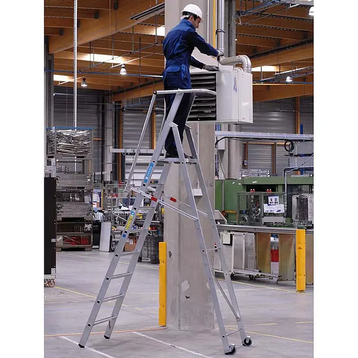 Zarges Stehleiter Stufenleiter ZAP Safemaster S mit großer Plattform 9 Stufen - Anzahl Tritte: 9 Stk., Arbeitshöhe: 4.340 m, Aluminium - Arbeiter auf hoher Alu-Podestleiter mit Rollen, führt Wartungsarbeiten in einer Fabrik durch.
