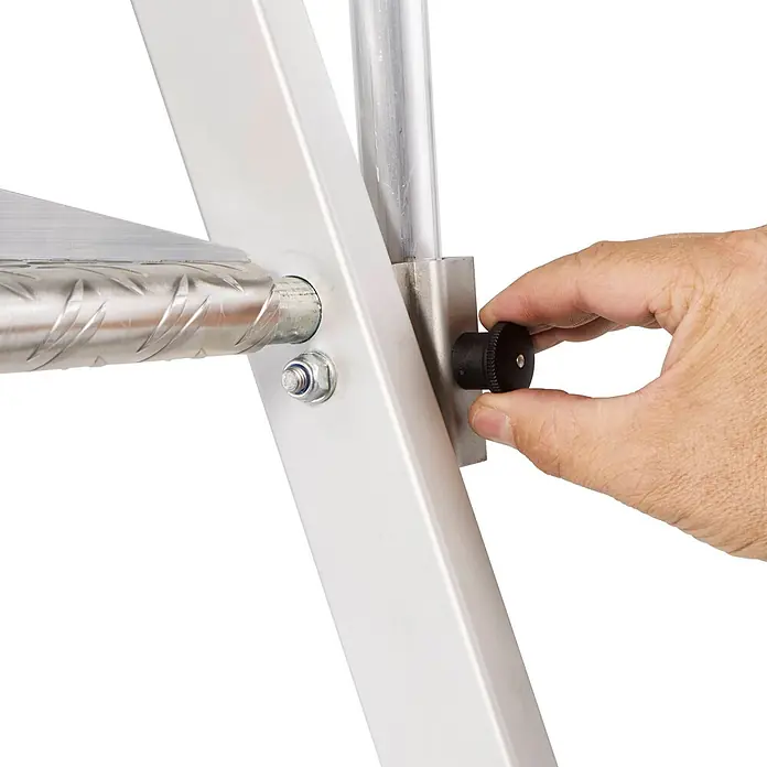 Zarges Podestleiter Plattformleiter ZAP Neo S mit klappbarem Handlauf 3 Stufen - Anzahl Tritte: 3 Stk., Arbeitshöhe: 2.740 m, Aluminium - Hand verstellt einen schwarzen Knopf an einer silbernen Aluminiumstruktur mit einer strukturierten Stufe.