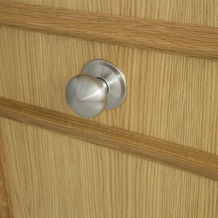 SegureStil Puerta de entrada interior S105 Serie V - 90 x 206 cm, Derecha, Roble claro, Acorazada - Primer plano de una puerta de madera con un elegante pomo redondo de metal cepillado en plata, que añade un toque de estilo moderno.