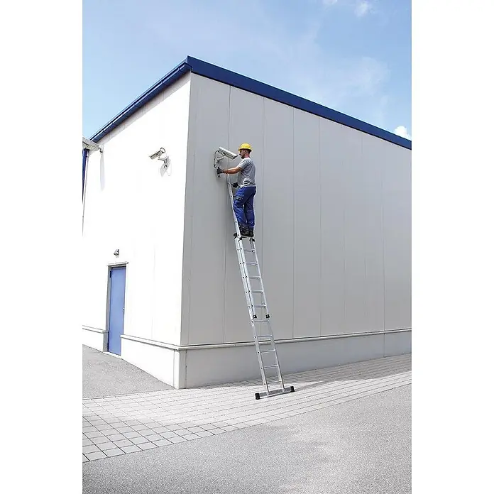 Munk Schiebeleiter Schiebeleiter mit Traverse 2x12 Sprossen - Anzahl Tritte: 12 Stk., Arbeitshöhe: 7.200 m, Aluminium - Mann auf silberner Ausziehleiter installiert Kamera.