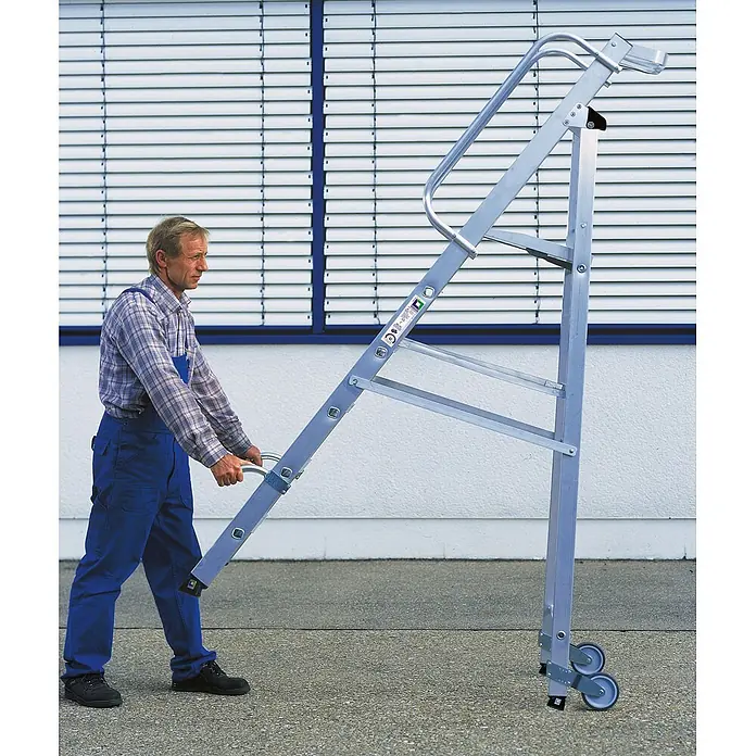Munk Stehleiter Aluminium-Stehleiter mit Rollen und Griff 6 Stufen - Anzahl Tritte: 6 Stk., Arbeitshöhe: 3.400 m, Aluminium - Mann transportiert eine silberne Aluminium-Stehleiter mit integrierten Rollen.