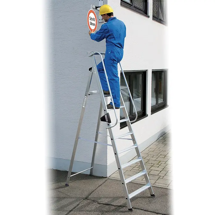 Munk Stehleiter Aluminium-Stehleiter 7 Stufen - Anzahl Tritte: 7 Stk., Arbeitshöhe: 3.650 m, Aluminium - Silberne Aluminium-Stehleiter, auf der ein Mann ein Schild anbringt.