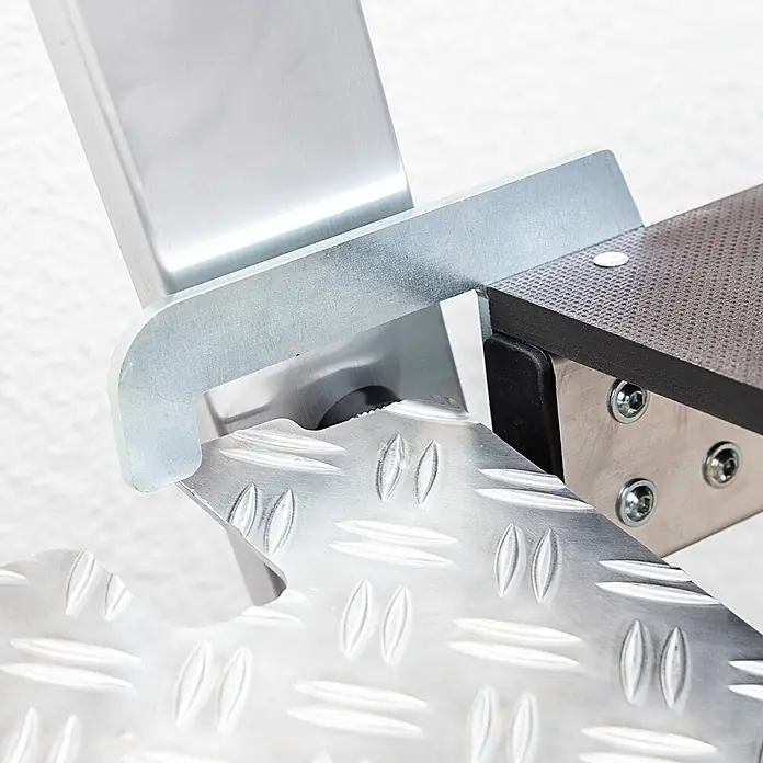 Munk Stehleiter Klapptritt beidseitig begehbar Alu natur 3 Stufen 2,73m AH - Anzahl Tritte: 3 Stk., Arbeitshöhe: 2.730 m, Aluminium - Nahaufnahme einer Metallrampenverbindung mit Riffelblech und einer dunklen, strukturierten Plattformplatte, die mit Schrauben befestigt ist.
