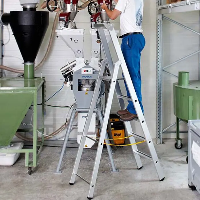 Zarges Stehleiter gebördelte Stehleiter Saferstep S eloxiert 10 Stufen - Anzahl Tritte: 10 Stk., Arbeitshöhe: 4.650 m, Aluminium - Silberne Aluminium-Klappleiter, von einer Person in industrieller Umgebung genutzt.
