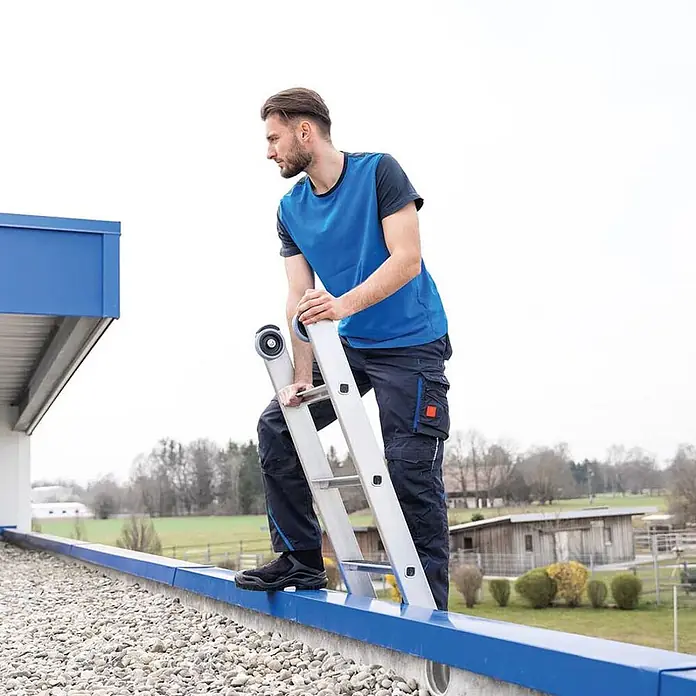 Munk Seilzugleiter Stufen- Seilzugleiter mit Nivello-Traverse und clip-step R13 2x12 Stufen - Anzahl Tritte: 12 Stk., Arbeitshöhe: 7.000 m, Aluminium - Silberne Leiter für den Dachzugang, sicher von einem Arbeiter über einer blauen Dachkante platziert.