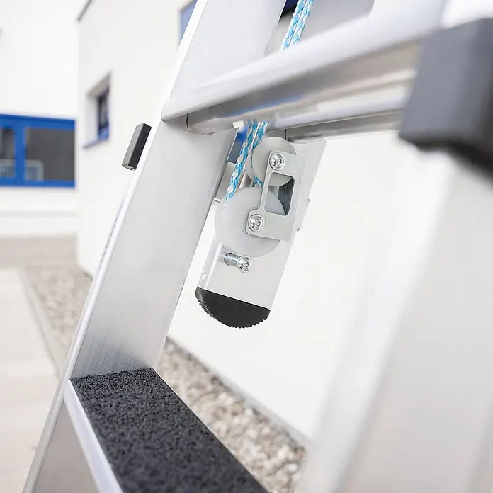 Munk Seilzugleiter Stufen- Seilzugleiter 2-teilig mit Handlauf und Ausstiegsholm 2x12 Stufen - Arbeitshöhe: 7.000 m, Belastbarkeit: 150 kg, Aluminium - Nahaufnahme einer Aluminium-Ausziehleiter mit blau-weißer Seilzugmechanik, einer schwarzen Antirutsch-Stufe und einem schwarzen Gummifuß.