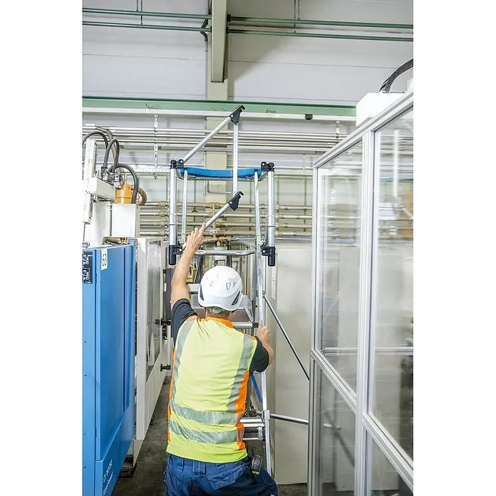 Zarges Teleskopleiter Teleskop Plattformleiter ZAP Masterflex Plus S gebördelt 3-5 Stufen - Anzahl Tritte: 5 Stk., Arbeitshöhe: 3.280 m, Belastbarkeit: 150 kg, Aluminium - Arbeiter montiert eine mobile Aluminium-Arbeitsbühne in einer Industriehalle.