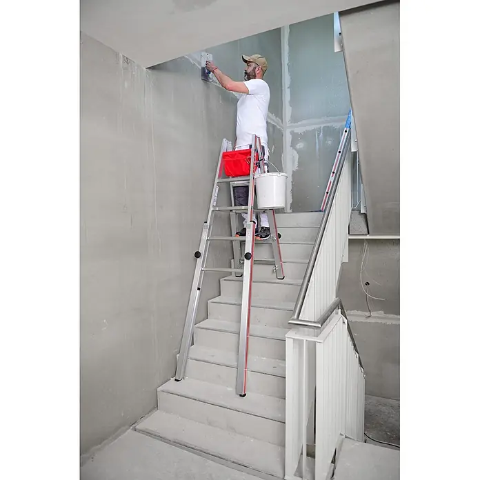 Hymer Teleskopleiter Treppenstehleiter Teleskopleiter mit patentierter Feststellvorrichtung 2x7 - Anzahl Tritte: 7 Stk., Arbeitshöhe: 3.300 m, Aluminium - Maler auf einer silber-roten Leiter, sicher an einer Wand im Treppenhaus arbeitend.