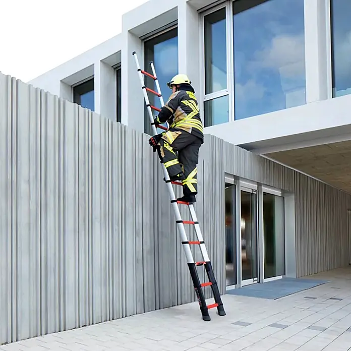 Telesteps Teleskopleiter Anlegeleiter Rescue Line Militär 13 Sprossen 4,1m - Anzahl Tritte: 13 Stk., Arbeitshöhe: 5.000 m, Belastbarkeit: 500 kg, Aluminium - Feuerwehrmann steigt auf eine silber-schwarze Teleskopleiter mit roten Akzenten an einem modernen Gebäude.