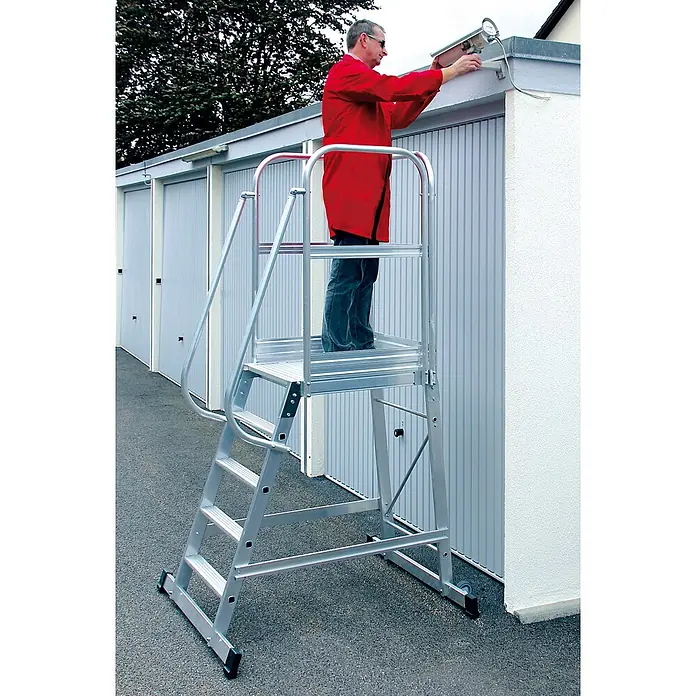 Munk Treppenpodest Podesttreppe einseitig begehbar fahrbar 4 Stufen - Anzahl Tritte: 4 Stk., Aluminium - Mann auf silberner Aluminium-Treppenplattform, der eine Überwachungskamera justiert.