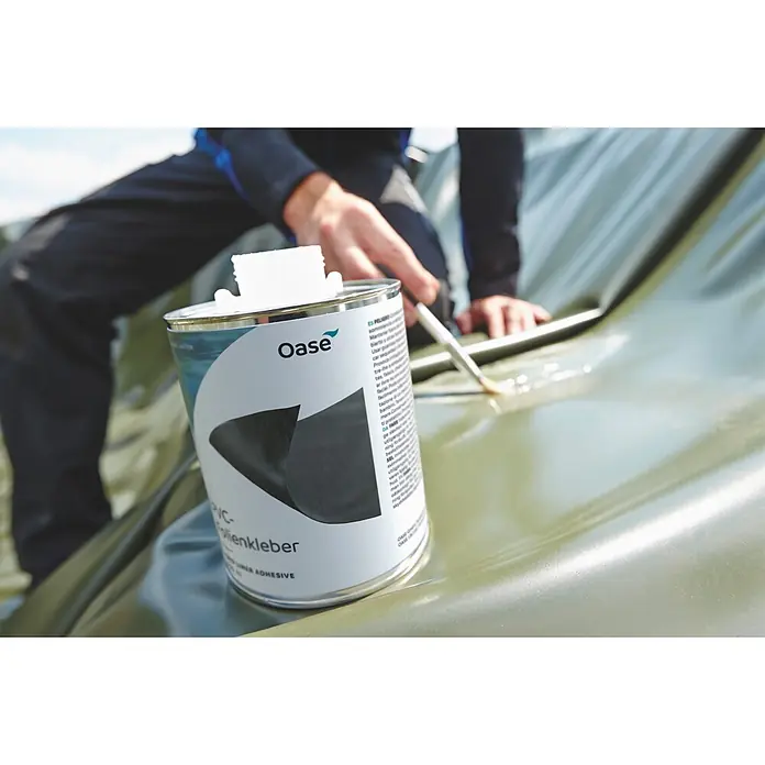 Oase PVC-Folienkleber - 250 ml - Oase PVC-Teichfolienkleber in der Dose wird mit Pinsel auf grüne Teichfolie aufgetragen.