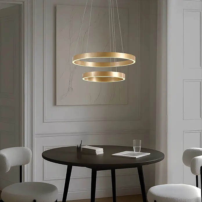 Lucande Pendelleuchte Yonam - L x B x H: 60 x 60 x 4,5 cm, messing / gold, gold, weiß - Zwei goldene ringförmige Pendelleuchten, von innen beleuchtet, hängen über einem dunklen runden Tisch im Esszimmer.
