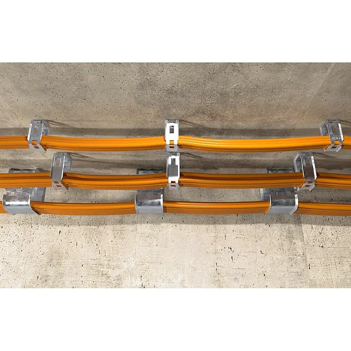 Fischer Halter Smmaelhalter für Kabel SHA M 15 - 15 mm, 50 Stk. - Silberne Metallklemmen befestigen mehrere orangefarbene Kabel an einer Betonwand oder Decke.