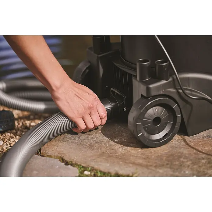 Oase Teichschlammsauger PondoVac 3 - 1.600 W, 27 l - Hand verbindet grauen Wellschlauch mit schwarzem Teichsauger auf einer Terrasse.