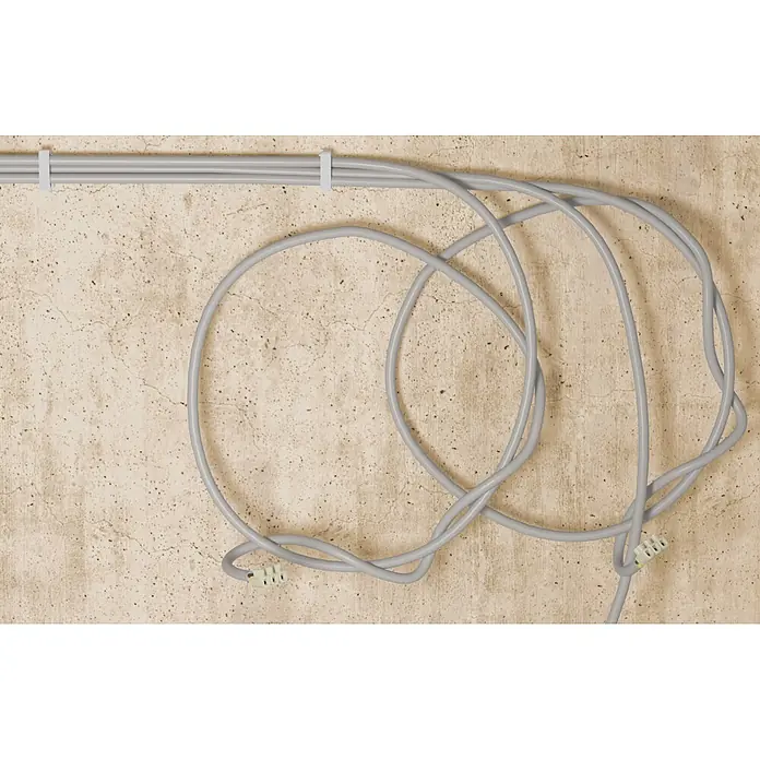 Fischer Kabelbinder mit Sockel - Für Kabel und Rohrleitungen von/bis 8 - 32 mm, 80 Stk. - Graue Kabel, mit einem weißen Kabelbinder an einer Betonwand befestigt, bilden Schleifen mit sichtbaren Steckern.