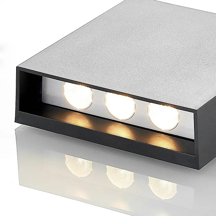 Lindby Außenwandleuchte Ugar - schwarz, schwarz, IP65 - Rechteckige, grau-schwarze LED-Wandleuchte mit drei warmweißen Lichtern, die sich auf der Oberfläche darunter spiegeln.