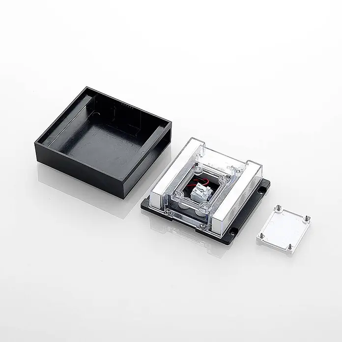 Lindby Außenwandleuchte Ugar - schwarz, schwarz, IP65 - Zerlegtes schwarzes Kunststoff-Elektrogehäuse mit klarer Abdeckung, interner Verkabelung, Klemmenblock und weißer Grundplatte.