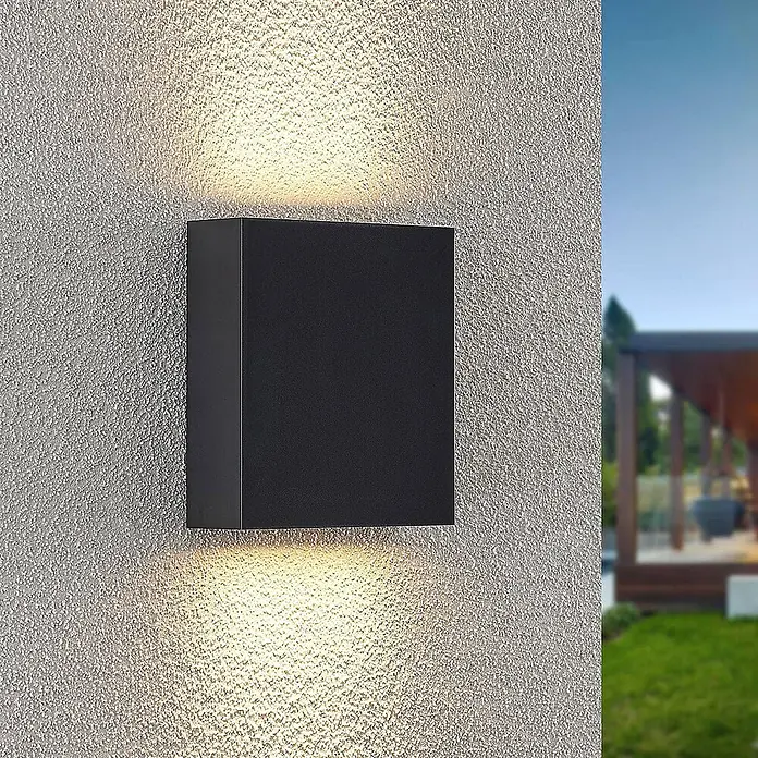 Lindby Außenwandleuchte Ugar - schwarz, schwarz, IP65 - Schwarze, quaderförmige Außenwandleuchte an strukturierter Wand, strahlt warmes Licht nach oben und unten.