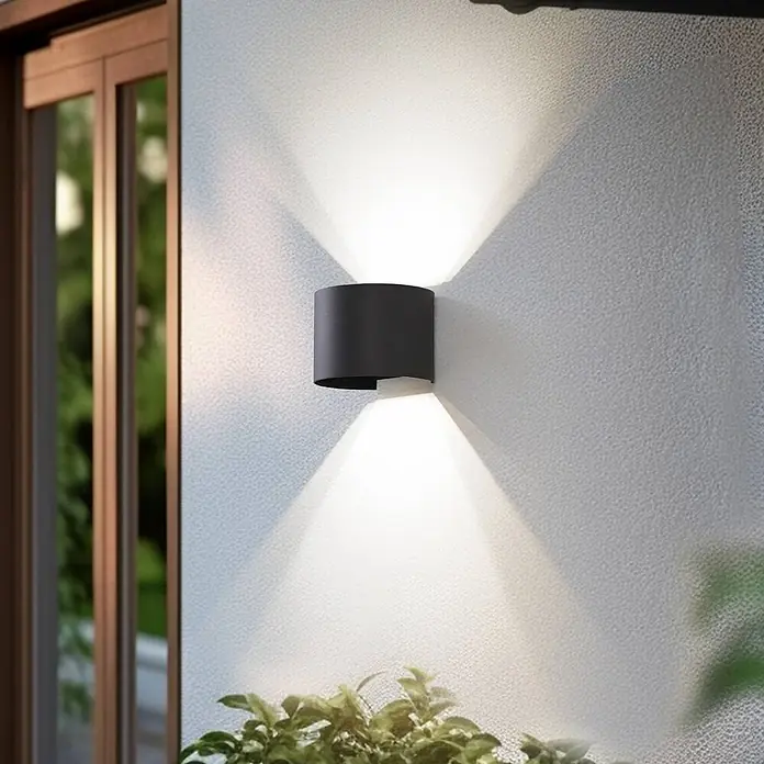Lindby Außenwandleuchte Dara - alu / grau / zink, IP54 - Dunkelgraue zylindrische Außenwandleuchte an texturierter Wand, wirft Licht nach oben und unten.