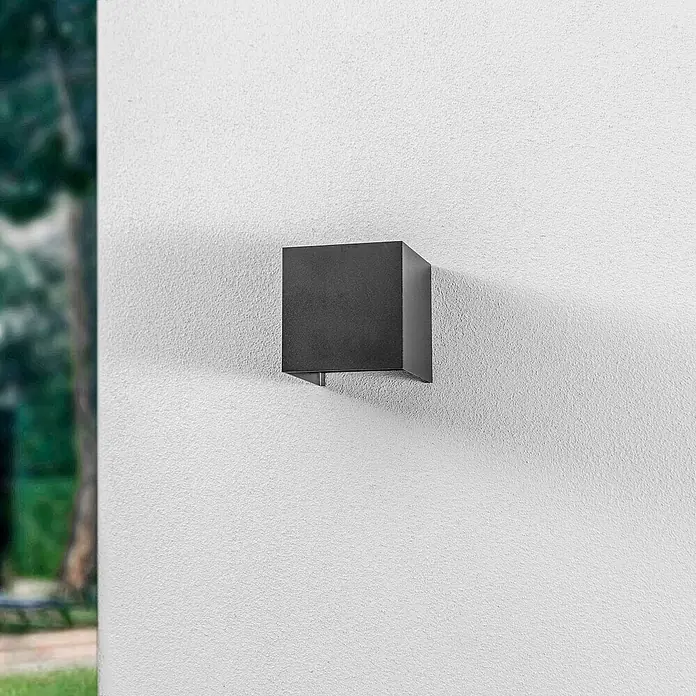 Lindby Außenwandleuchte Nivar - schwarz, IP54 - Schwarze, kubische Außenwandleuchte an einer strukturierten weißen Wand.