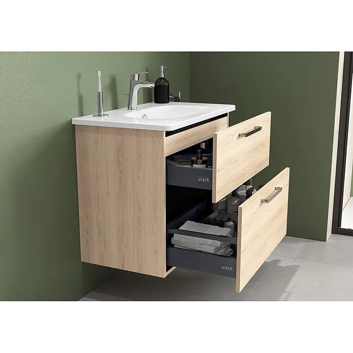 VitrA Badmöbel-Set Root Flat - B x T x H: 80 x 45 x 65 cm, Eiche Natur - Wandhängender Waschtischunterschrank aus hellem Holz, weißem Becken und zwei geöffneten dunkelgrauen Schubladen mit Toilettenartikeln und Handtüchern.
