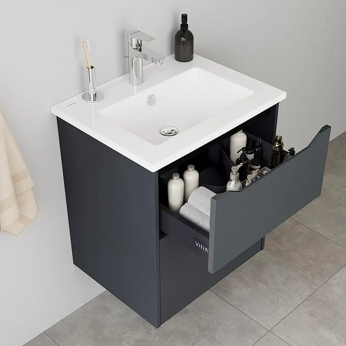 VitrA Integra Square Badmöbel-Set - Gesamtbreite Badmöbel: 60 cm, Graphit, Matt - Dunkelgrauer Badunterschrank mit weißem Waschbecken und offener Schublade mit Flaschen und Handtüchern.