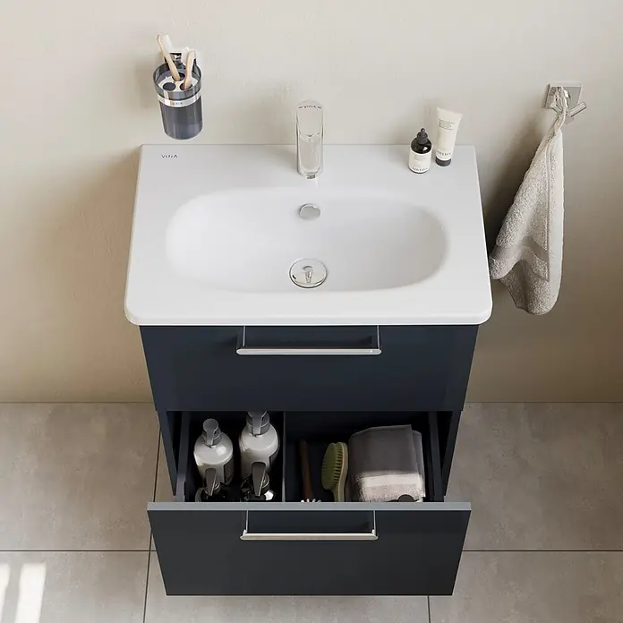 VitrA Root Flat Compact Badmöbel-Set Compact - B x T x H: 60 x 37 x 65 cm, Anthrazit, Hochglänzend - Dunkelgrauer Badunterschrank mit weißem Waschbecken und Chromarmatur, offene Schublade zeigt Toilettenartikel.