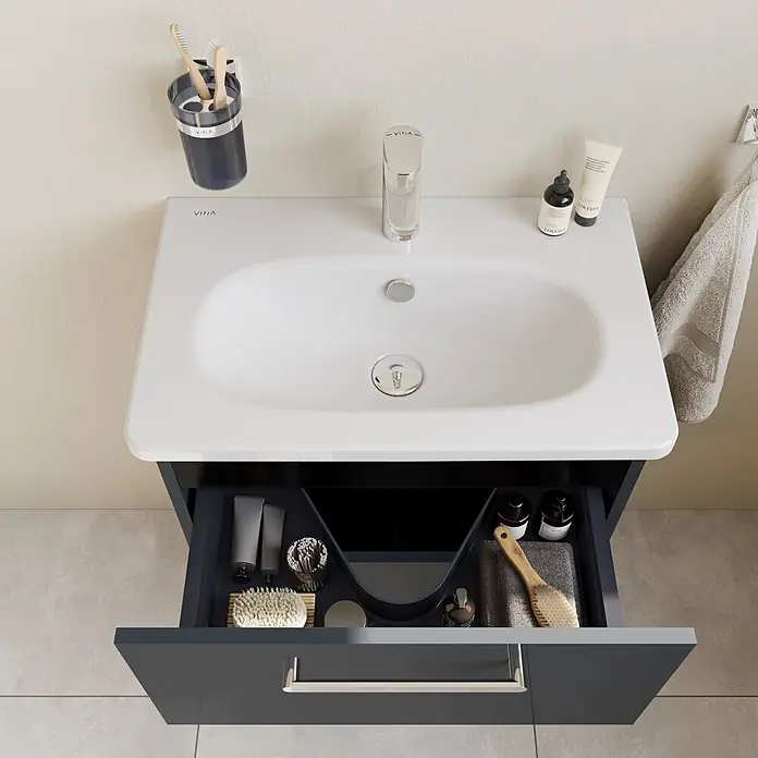 VitrA Root Flat Compact Badmöbel-Set Compact - B x T x H: 60 x 37 x 65 cm, Anthrazit, Hochglänzend - Ein moderner dunkelgrauer Badunterschrank mit integriertem weißen Waschbecken, Chromarmatur und geöffneter Schublade mit Toilettenartikeln.