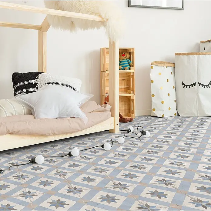 Feinsteinzeugfliese Vichy - 24,8 x 24,8 cm, Mar, Matt - Blaue, beige und graue Bodenfliesen mit Sternmuster bedecken den Boden eines Kinderzimmers.