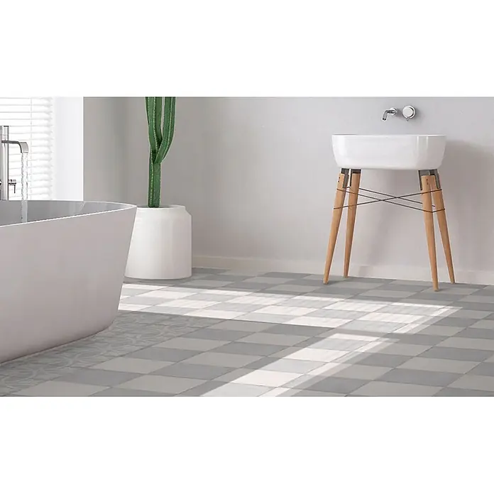 Feinsteinzeugfliese Triana - 24,8 x 24,8 cm, Gris, Matt - Stilvolles weißes Keramikwaschbecken mit schlanken Holzbeinen und einer freistehenden Badewanne in einem modernen Badezimmer.
