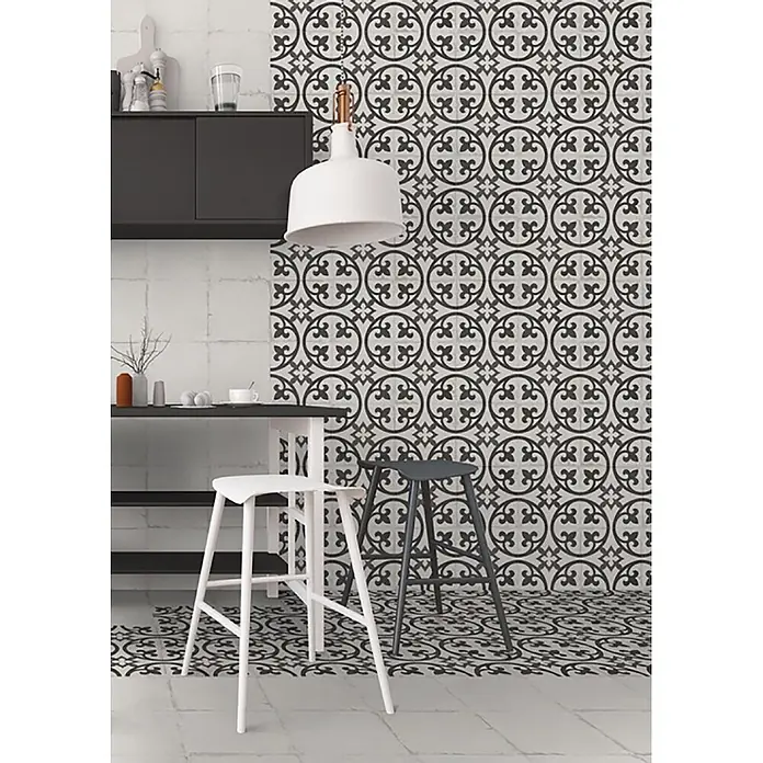 Feinsteinzeugfliese Chez Coco - 24,8 x 24,8 cm, Flora, Matt - Schwarz-weiß gemusterte Fliesen an Wand und Boden einer Küche mit geometrisch-floralem Design.