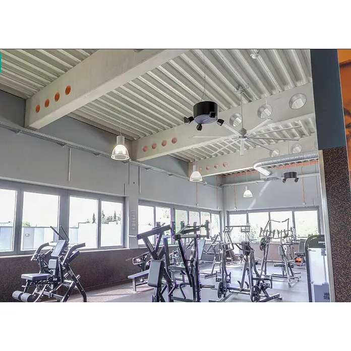 Vam Deckenventilator GIANT silber 245 cm - Bronze Aluminiumflügel, 2.450 mm, 34 W - Geräumiger Fitnessraum mit zahlreichen schwarzen und silbernen Trainingsgeräten, großen Fenstern und einer Industriedecke mit Ventilator.