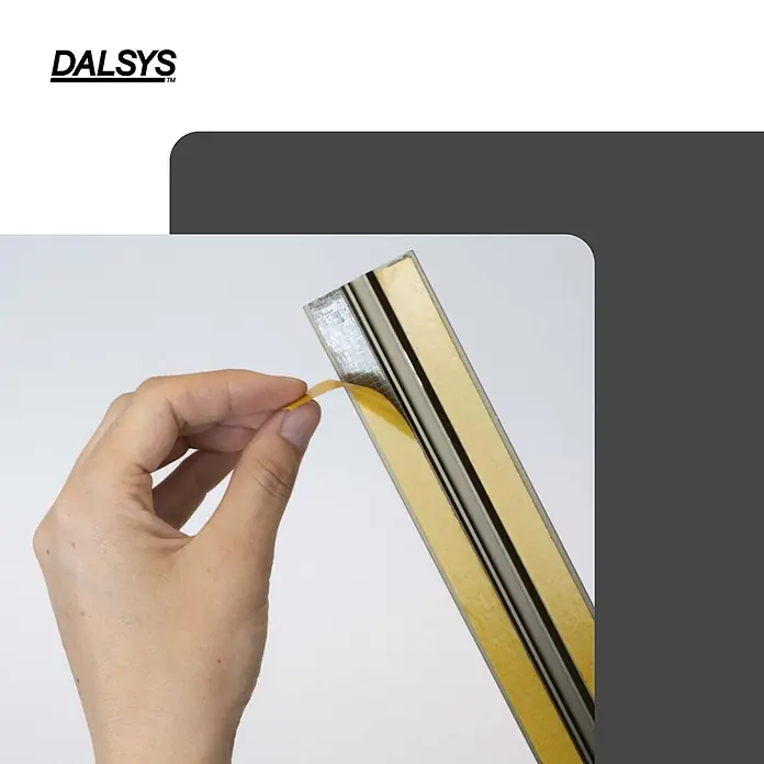 Dalsys Abschlussleiste 90cm Übergangsprofil Übergangsschiene Bronze selbstklebend -  - Metallleiste mit gelber Klebefolie, von einer Hand abgezogen, um die Klebefläche freizulegen.