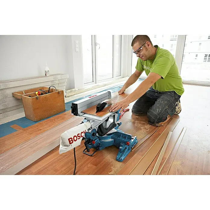 Bosch Professional Tischkreissäge GTM 12 JL - 1.800 W, Durchmesser Sägeblatt: 305 mm - Ein Handwerker benutzt eine Bosch Kappsäge für Holzarbeiten. Die Säge ist gut sichtbar und nimmt einen großen Teil des Bildes ein.