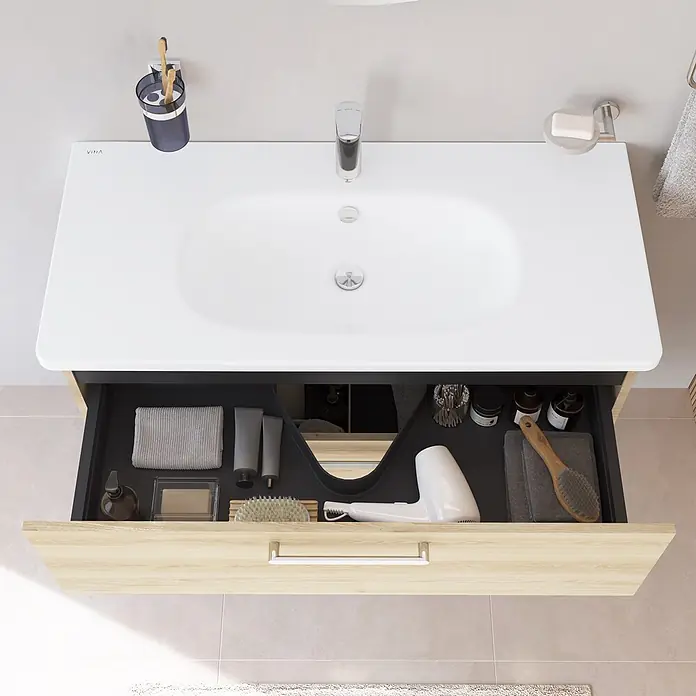 VitrA Badmöbel-Set Root Flat - B x T x H: 100 x 45 x 65 cm, Eiche Natur - Moderner Badwaschtisch mit weißem Becken und hellholzfarbener Schublade, geöffnet, um ordentlich organisierte Toilettenartikel, Handtücher und einen Haartrockner zu zeigen.