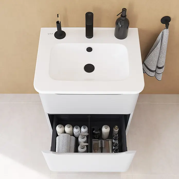 VitrA Integra Round Badmöbel-Set - Gesamtbreite Badmöbel: 60 cm, Hellgrau, Matt - Weißer VitrA Waschtisch mit integriertem Becken, schwarzen Armaturen und offenem Schubfach mit Pflegeprodukten.