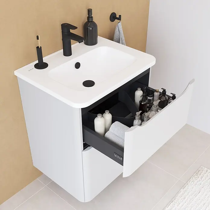 VitrA Integra Round Badmöbel-Set - Gesamtbreite Badmöbel: 60 cm, Hellgrau, Matt - Weißer Badezimmerschrank mit integriertem Waschbecken und schwarzer Armatur. Die offene Schublade zeigt ordentliche Toilettenartikel und ein Handtuch im modernen Bad.