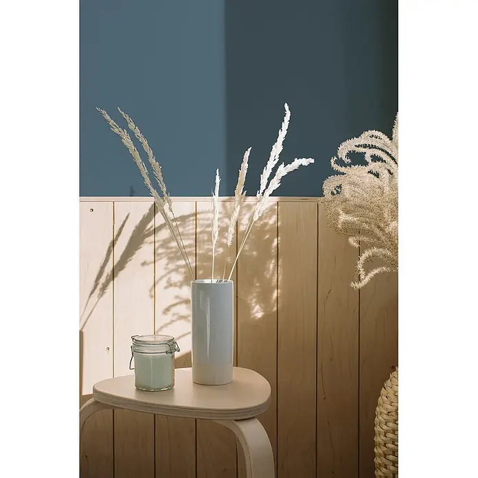 Livingwalls Wandfarbe Blau, Bluish Petrol DD125912 2,5l - Grün, Matt, 2,5 l - Getrocknetes weißes Gras in einer Keramikvase und eine Kerze auf einem hellen Holztisch.