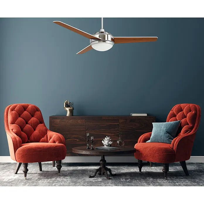 Vam Deckenventilator VEGALIGHT chrom weiß/Kirschholz - Chrom - Kirsche, 1.320 mm, 46 W - Gemütliches Wohnzimmer mit orangefarbenen Samtsesseln, dunklem Holztisch und Sideboard, dazu Deckenventilator vor blauer Wand.