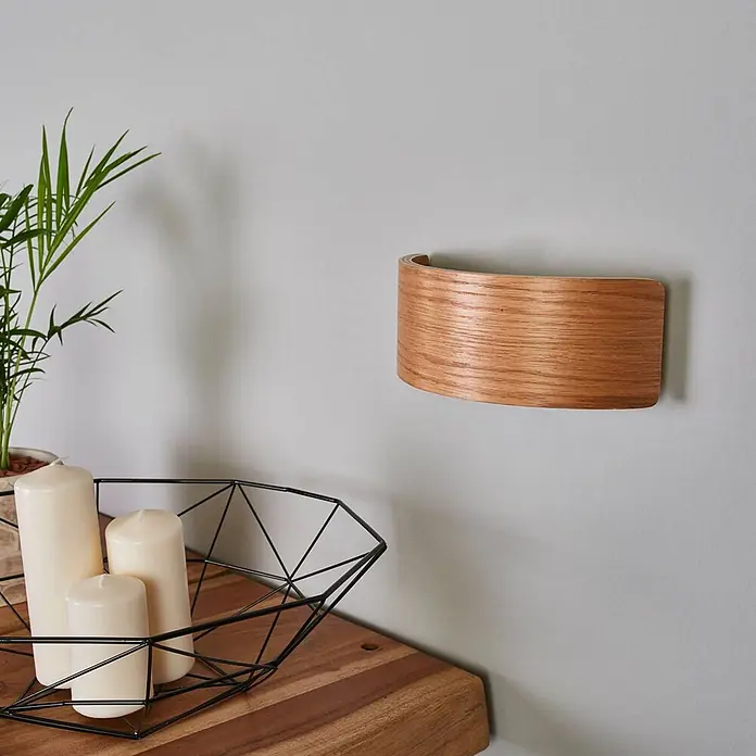 Lindby Wandleuchte Rafailia - Holz dunkel - Geschwungene Wandleuchte aus hellem Holz, an der Wand montiert, in einem Wohnambiente.