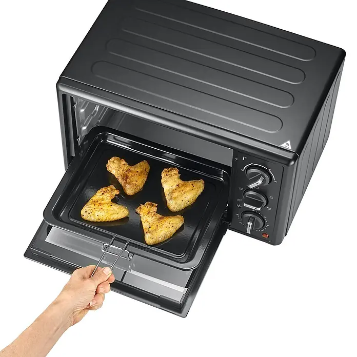 Severin Minibackofen TO2079 - Max. Leistung: 1.400 W, 20 l - Eine Hand zieht ein Blech mit goldenen Hähnchenflügeln aus einem schwarzen Mini-Ofen.
