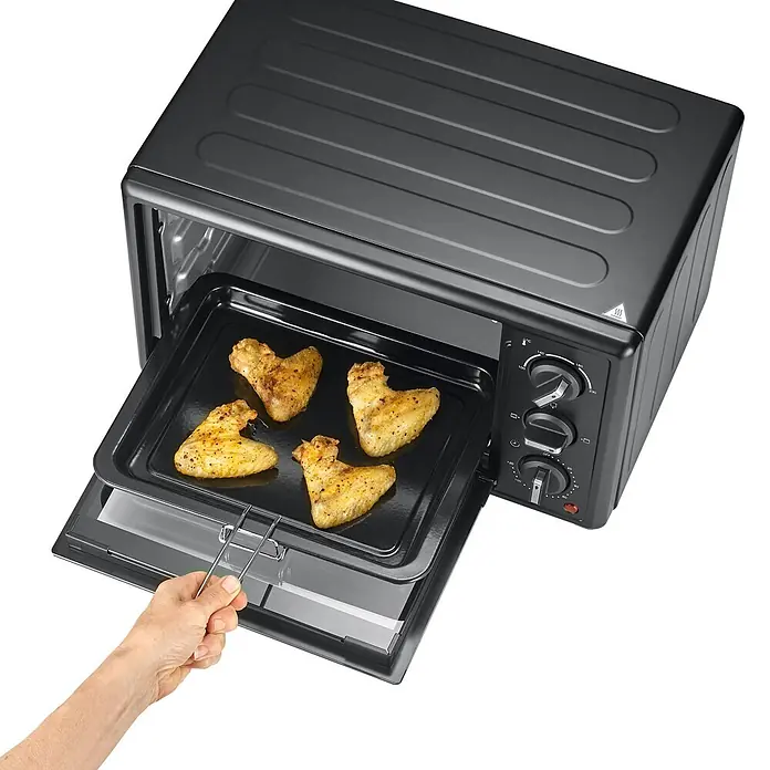 Severin Minibackofen TO2078 - Max. Leistung: 1.400 W, 20 l - Schwarzer Mini-Ofen, eine Hand zieht ein Blech mit goldenen Hähnchenflügeln heraus.