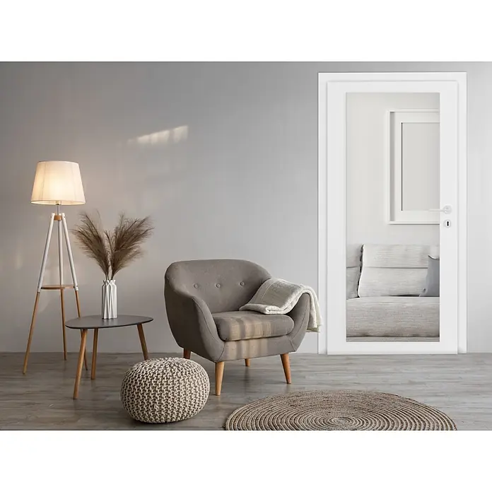Kristall-Form Türspiegel Touch - B x H: 60 x 160 cm - Eine moderne Wohnzimmerszene mit grauem Sessel, Stehlampe, Strickpouf und gewebtem Teppich auf hellem Boden.