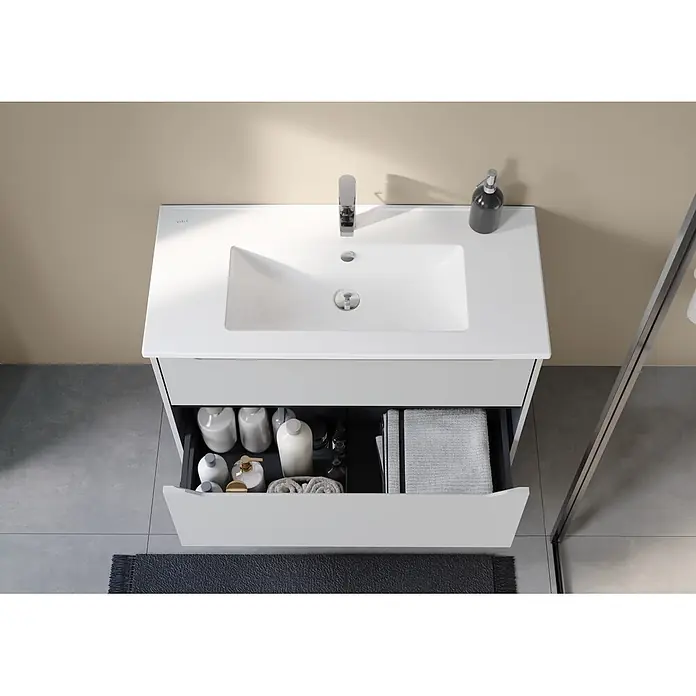 VitrA Integra Square Badmöbel-Set - Gesamtbreite Badmöbel: 100 cm, Hellgrau, Matt - Hellgrauer Badezimmerunterschrank mit weißem integriertem Waschbecken, Chromarmatur und geöffneter Schublade mit Pflegeprodukten und Handtüchern.