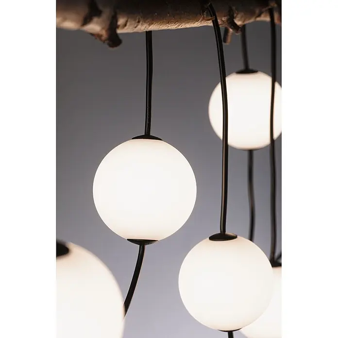 Paulmann Plug & Shine LED-Lichterkette Naima Basisset - Außen, Warmweiß, Anzahl Leuchtmittel: 6 Stk., Länge: 5,8 m, Netzbetrieben - Moderne Hängeleuchte mit mehreren weißen Kugel-Diffusoren, die an schwarzen Kabeln von einem Naturholzast hängen.
