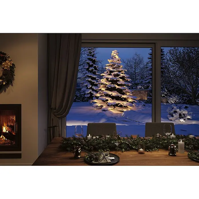 Paulmann Plug & Shine LED-Lichterkette Yuna - Außen, RGB, Länge: 7,4 m - Gemütlicher festlicher Essbereich mit Kamin und gedecktem Tisch, Blick auf verschneiten Garten mit beleuchtetem Weihnachtsbaum.