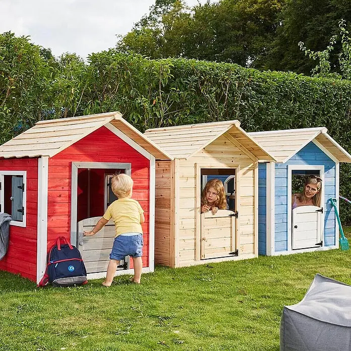 Home Deluxe Spielhaus DER GROSSE PALAST - L x B x H: 111 x 118,2 x 132,5 cm, Holz, Natur - Drei bunte Holz-Spielhäuser im Garten, von Kindern und einem Erwachsenen genutzt.